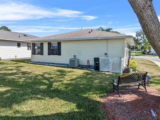 rear view of property with roof with shingles, a lawn, and cooling unit