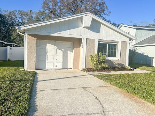 view of front facade with an attached garage, fence, driveway, stucco siding, and a front yard