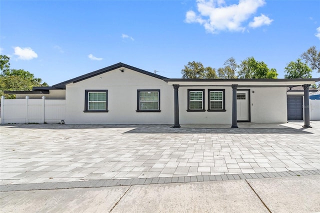 exterior space with stucco siding, decorative driveway, an attached garage, and fence