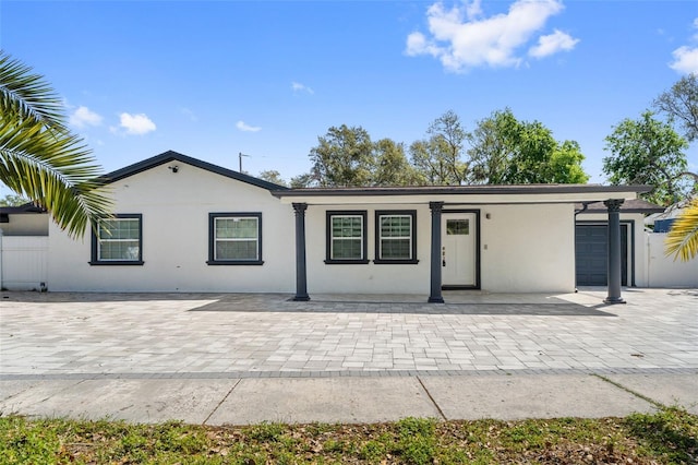 ranch-style house featuring stucco siding, a garage, and fence