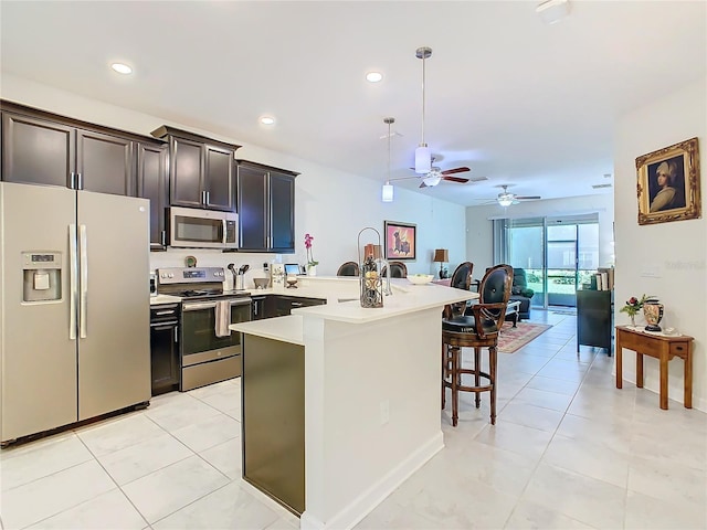 kitchen featuring a breakfast bar, light tile patterned floors, stainless steel appliances, and light countertops