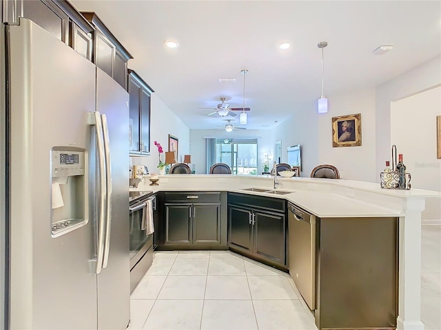 kitchen featuring light countertops, hanging light fixtures, appliances with stainless steel finishes, a sink, and a peninsula