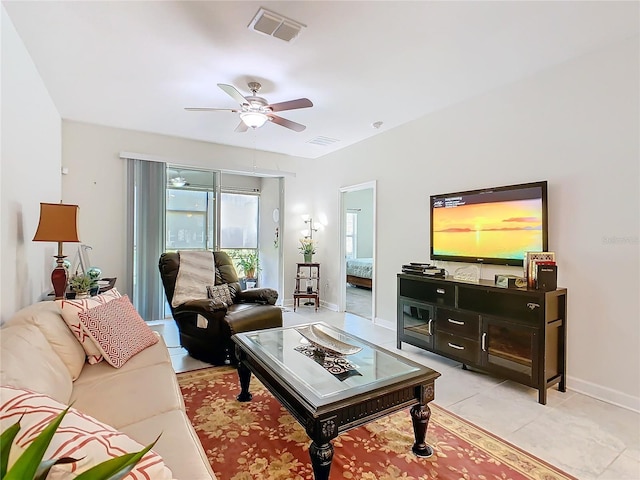 living area with ceiling fan, light tile patterned floors, visible vents, and baseboards