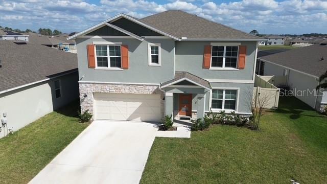 view of front of property featuring stone siding, a front yard, driveway, and stucco siding