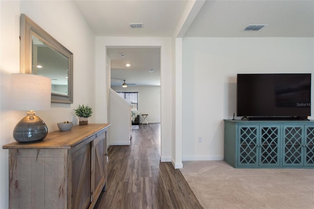 hallway with visible vents, baseboards, and wood finished floors