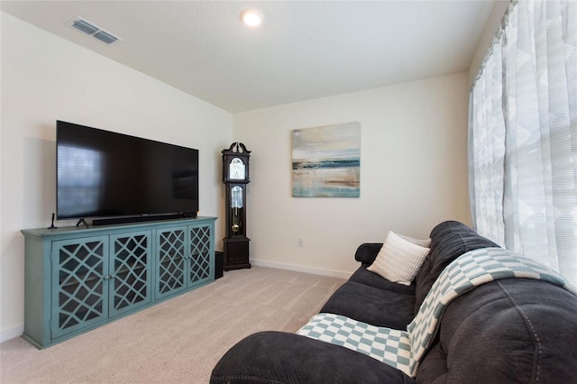 living area featuring baseboards, visible vents, and light colored carpet