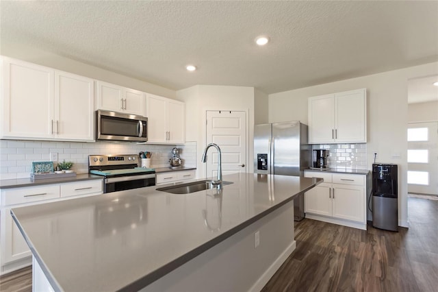 kitchen featuring appliances with stainless steel finishes, a sink, a kitchen island with sink, and white cabinets