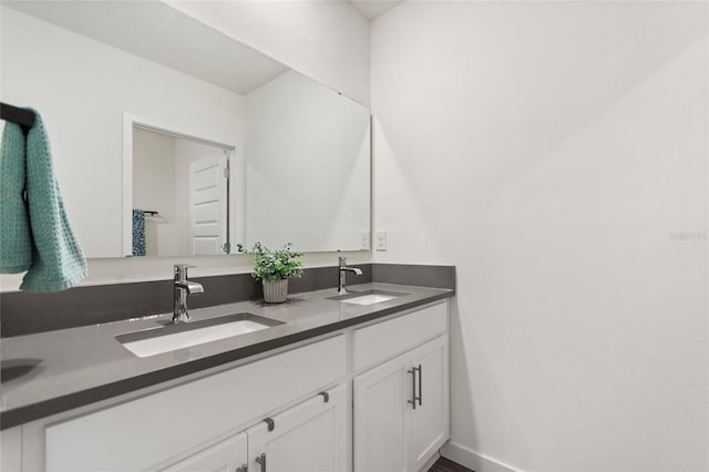 bathroom with a sink, baseboards, and double vanity