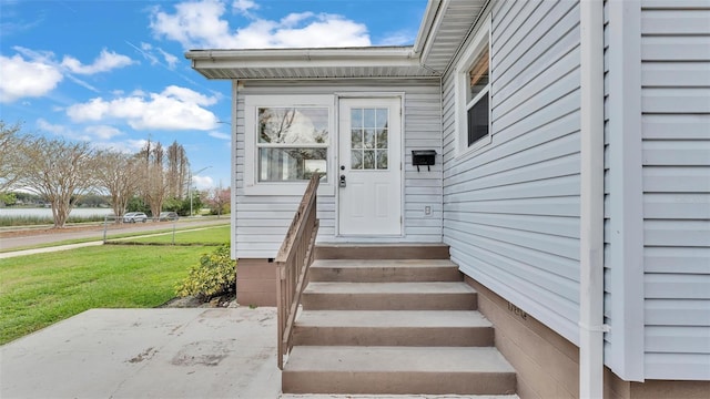 entrance to property featuring crawl space and a lawn