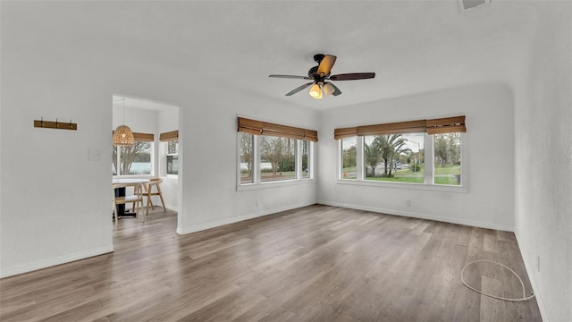 unfurnished room featuring a ceiling fan, visible vents, baseboards, and wood finished floors