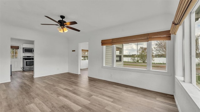 empty room featuring ceiling fan, wood finished floors, and baseboards