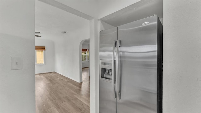 kitchen with arched walkways, baseboards, wood finished floors, and stainless steel fridge with ice dispenser