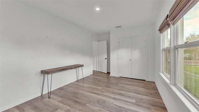 unfurnished bedroom featuring a closet, visible vents, baseboards, and light wood finished floors