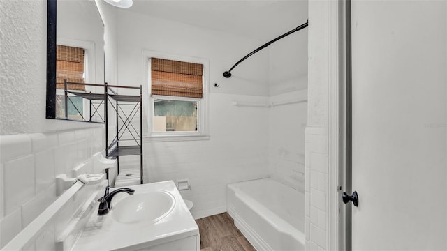 full bathroom with plenty of natural light, tile walls, vanity, and wood finished floors