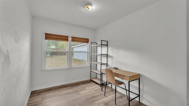 office featuring a textured wall, wood finished floors, and baseboards