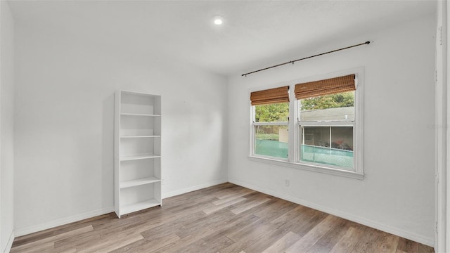 spare room featuring baseboards and wood finished floors