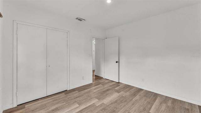 unfurnished bedroom with light wood finished floors, a closet, visible vents, and baseboards