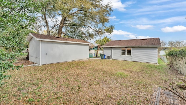 back of property featuring an outbuilding, cooling unit, a yard, and fence