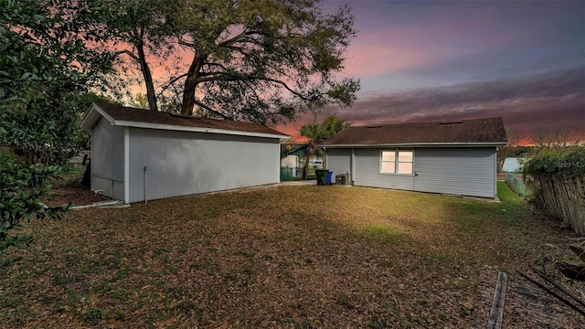 back of property with an outbuilding, a yard, central AC unit, and fence