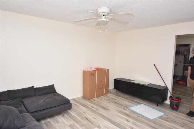 living area featuring a textured ceiling, light wood-type flooring, and a ceiling fan