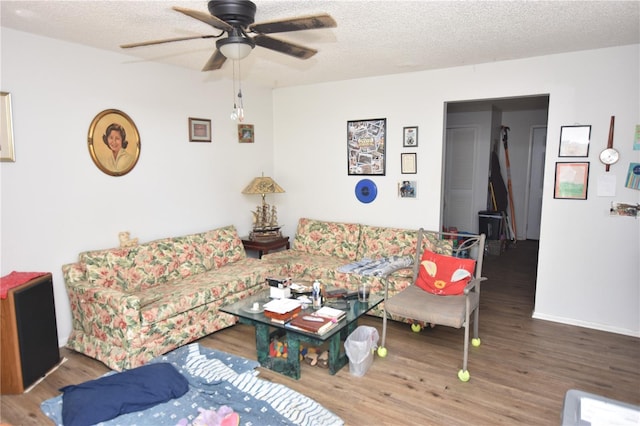 living room with a textured ceiling, ceiling fan, wood finished floors, and baseboards