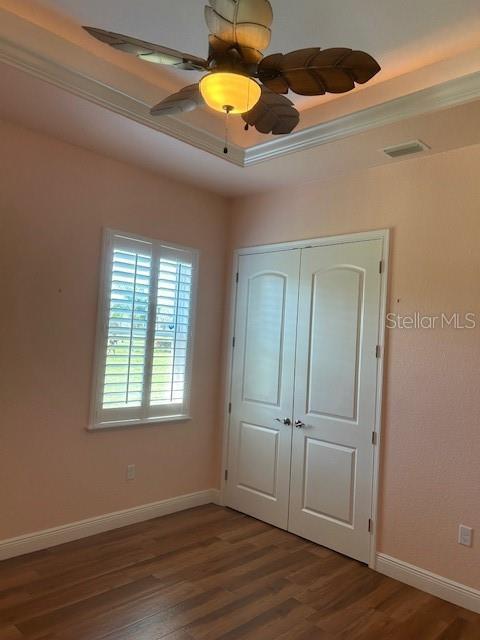 unfurnished bedroom with a closet, wood finished floors, and baseboards