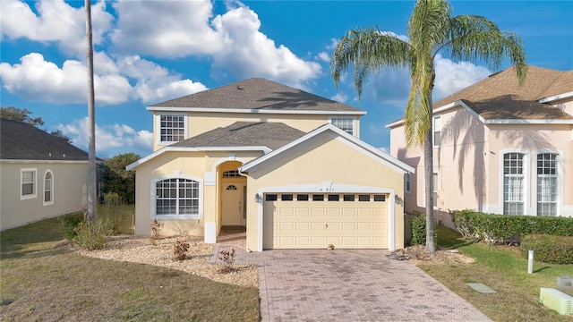 view of front of home featuring a front lawn, decorative driveway, an attached garage, and stucco siding