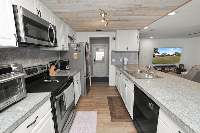 kitchen with stainless steel appliances, a sink, white cabinetry, light wood finished floors, and tasteful backsplash