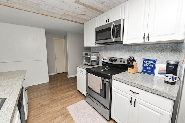 kitchen with stainless steel appliances, tile counters, and white cabinets