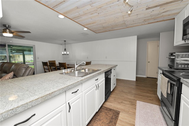 kitchen with tile counters, white cabinets, stainless steel appliances, pendant lighting, and a sink