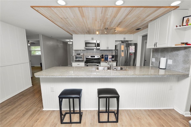 kitchen featuring a peninsula, appliances with stainless steel finishes, white cabinetry, and a kitchen breakfast bar