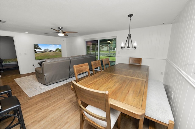 dining area featuring light wood finished floors, visible vents, and ceiling fan with notable chandelier