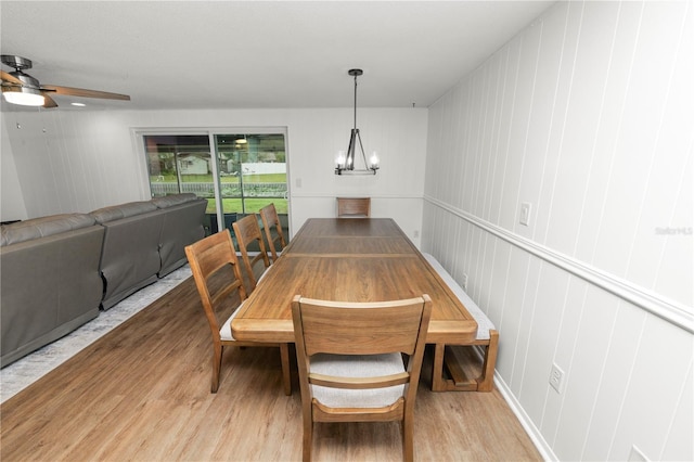 dining space featuring light wood-style floors and ceiling fan with notable chandelier