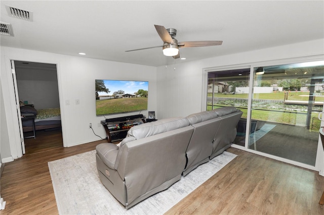 living area with a ceiling fan, baseboards, visible vents, and wood finished floors