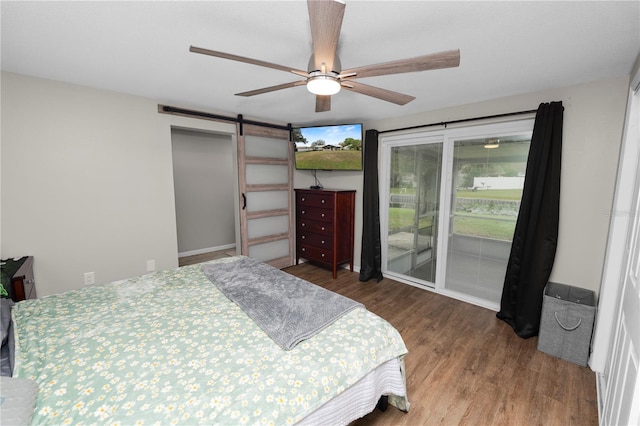 bedroom featuring access to exterior, wood finished floors, ceiling fan, and a barn door