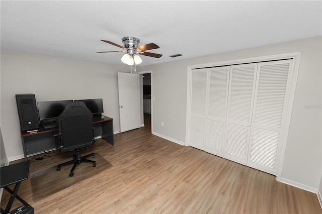 office space featuring visible vents, baseboards, a ceiling fan, light wood-style flooring, and a textured ceiling