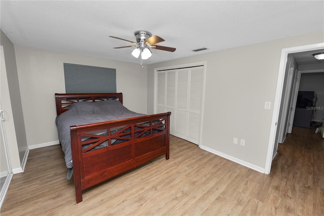 bedroom with a closet, light wood-type flooring, visible vents, and baseboards