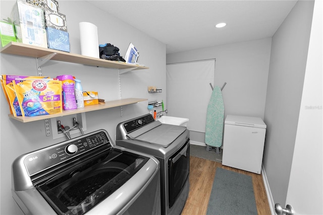 clothes washing area featuring washing machine and clothes dryer, dark wood-type flooring, a sink, laundry area, and baseboards