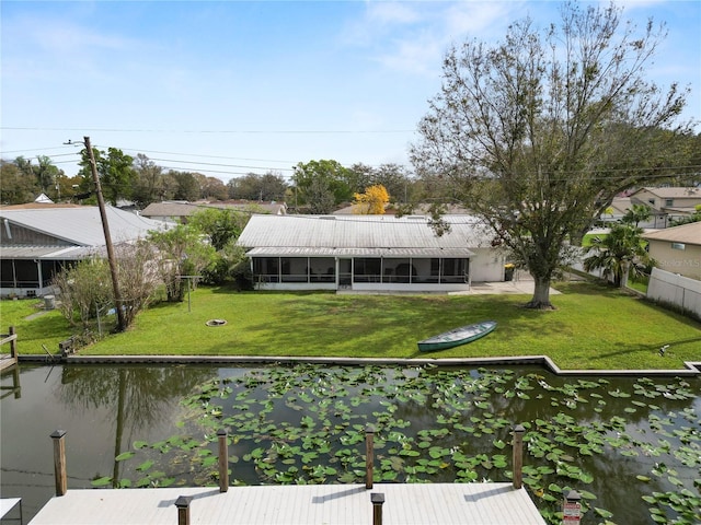 back of property featuring a water view, a sunroom, and a yard