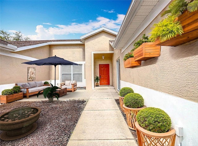 view of exterior entry featuring a patio area, outdoor lounge area, and stucco siding