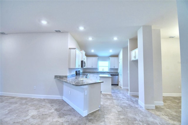 kitchen with a peninsula, a sink, visible vents, white cabinetry, and appliances with stainless steel finishes