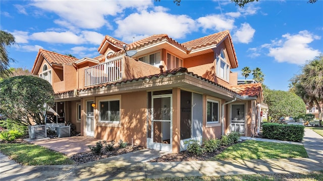 exterior space featuring a patio area, a tile roof, a balcony, and stucco siding