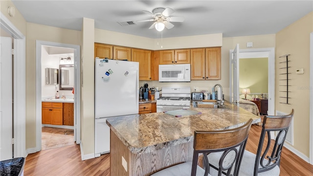 kitchen with light wood-style flooring, white appliances, a sink, visible vents, and brown cabinets