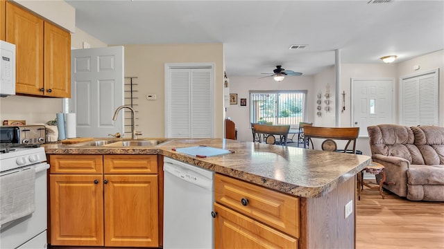 kitchen featuring white appliances, visible vents, ceiling fan, open floor plan, and a sink