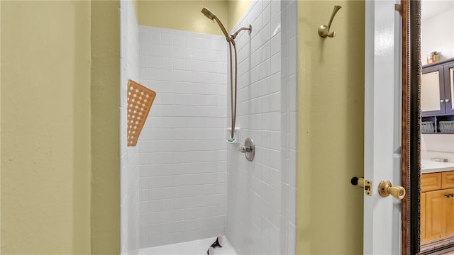 full bathroom with tiled shower and vanity