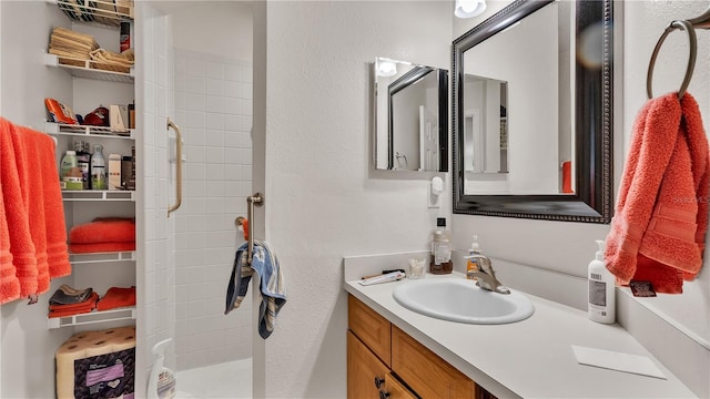 full bathroom featuring a textured wall and vanity