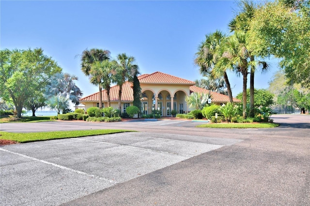 view of front of property featuring uncovered parking, a tile roof, and stucco siding