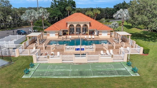 community pool featuring a yard, fence, and shuffleboard