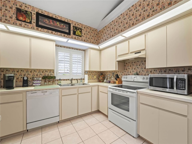 kitchen with light countertops, cream cabinets, a sink, white appliances, and under cabinet range hood