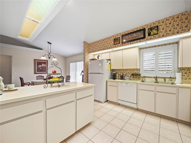 kitchen featuring light countertops, white appliances, hanging light fixtures, and a sink